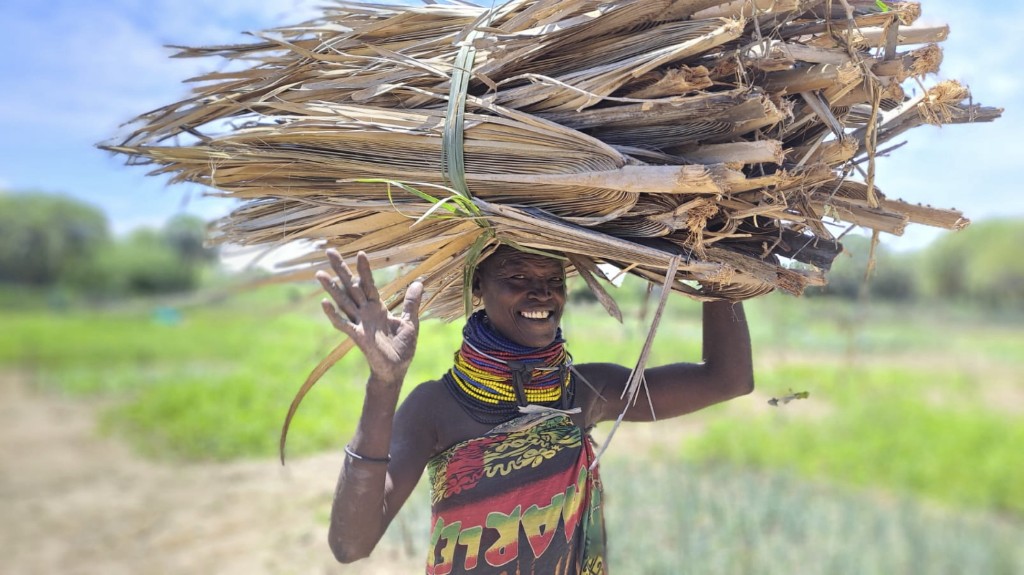 Community member carrying harvested materials in a rural landscape